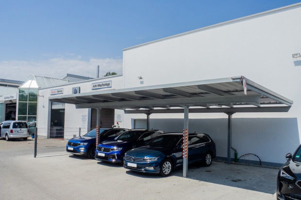 Autos unter einem Carport vor einer Autowaschanlage