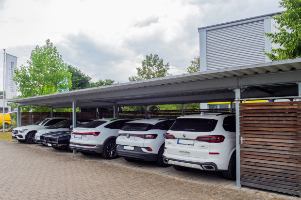 Autos unter einem Carport vor einer Firma